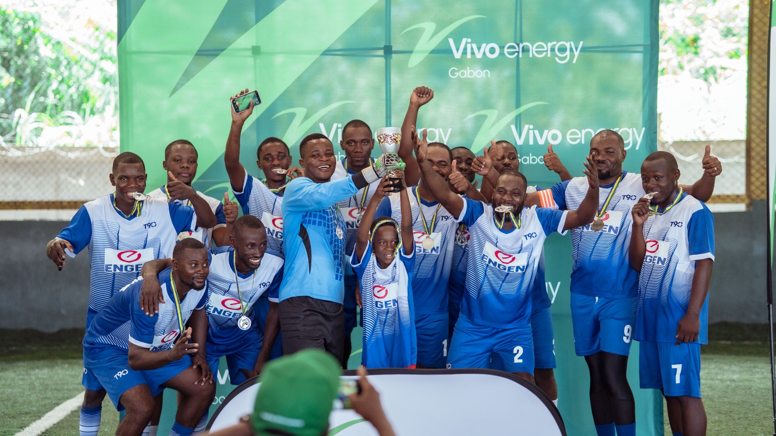 The winning football team cheer and raise their trophy