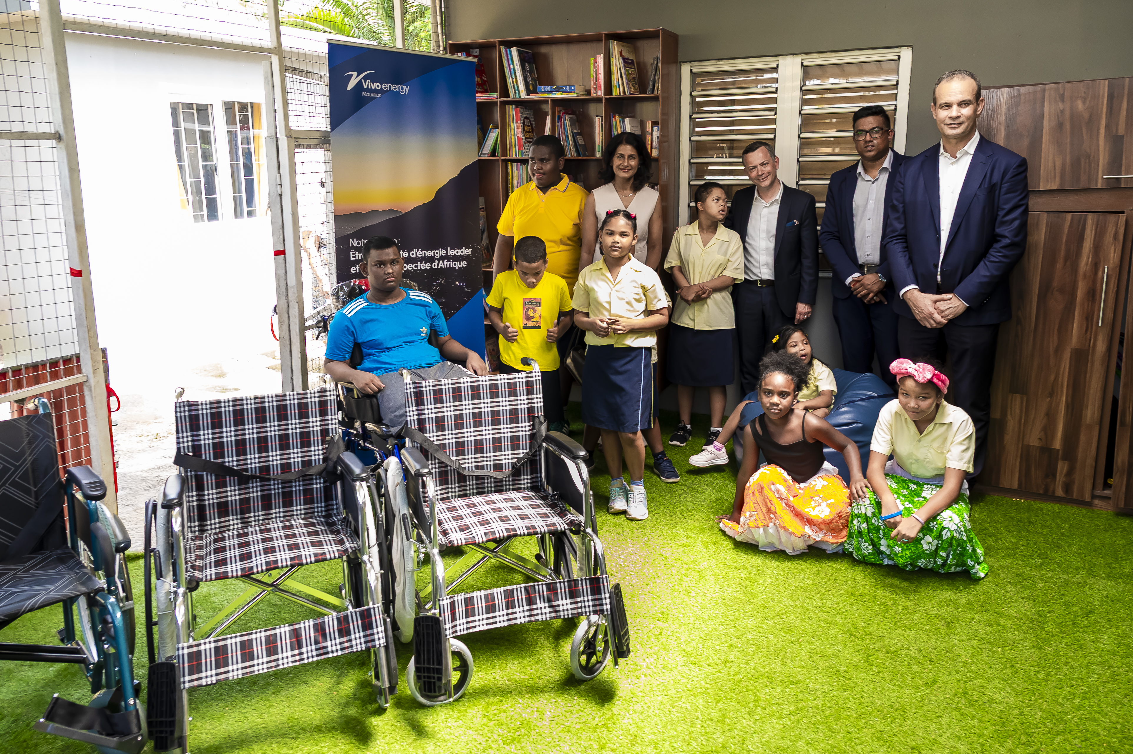 Vivo Energy representatives stand beside children supported by the NGO Reve & Espoir. Donated wheelchairs sit in the foreground.