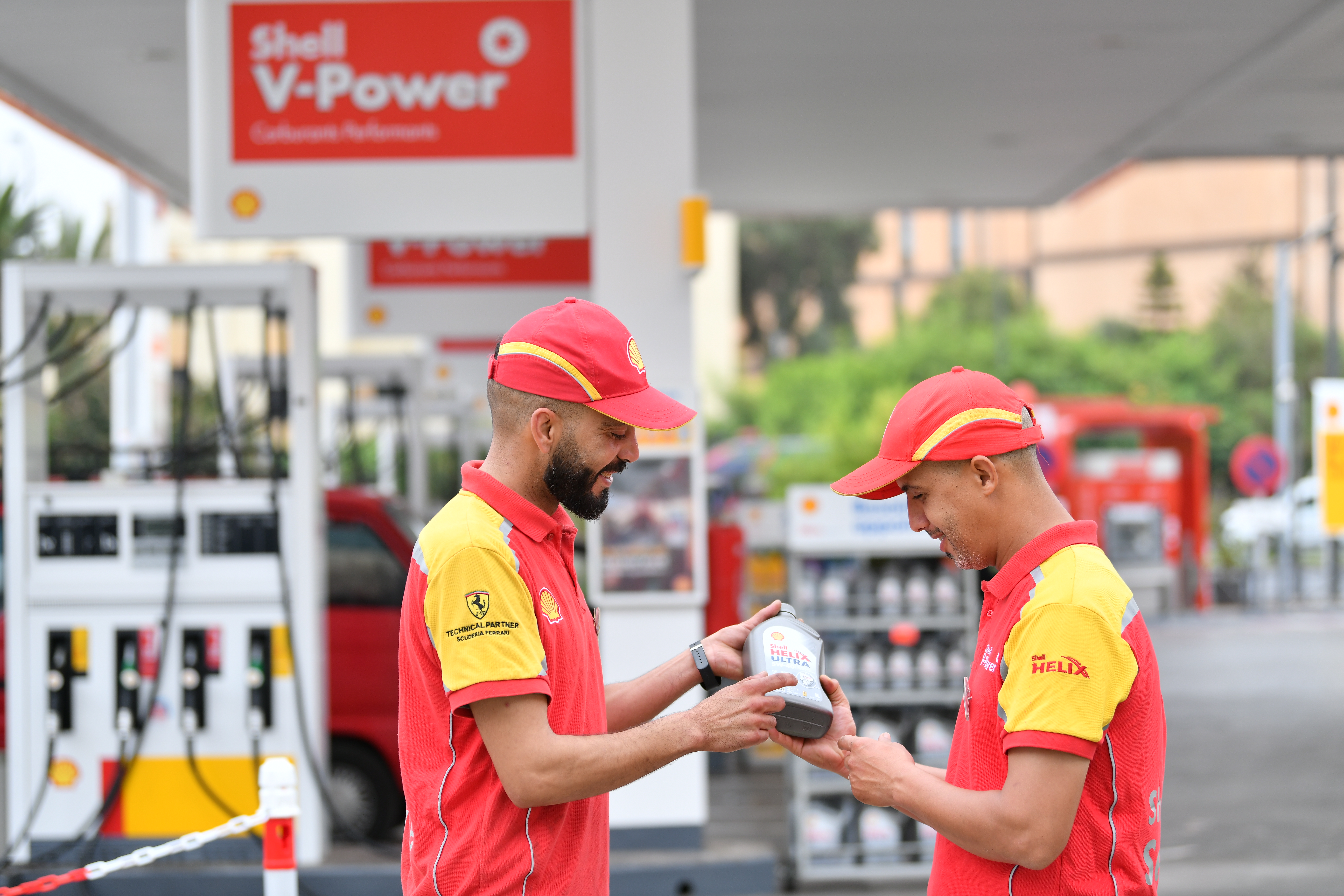 Two Shell pump attendants, or Customer Champions, hold a bottle of Shell Helix